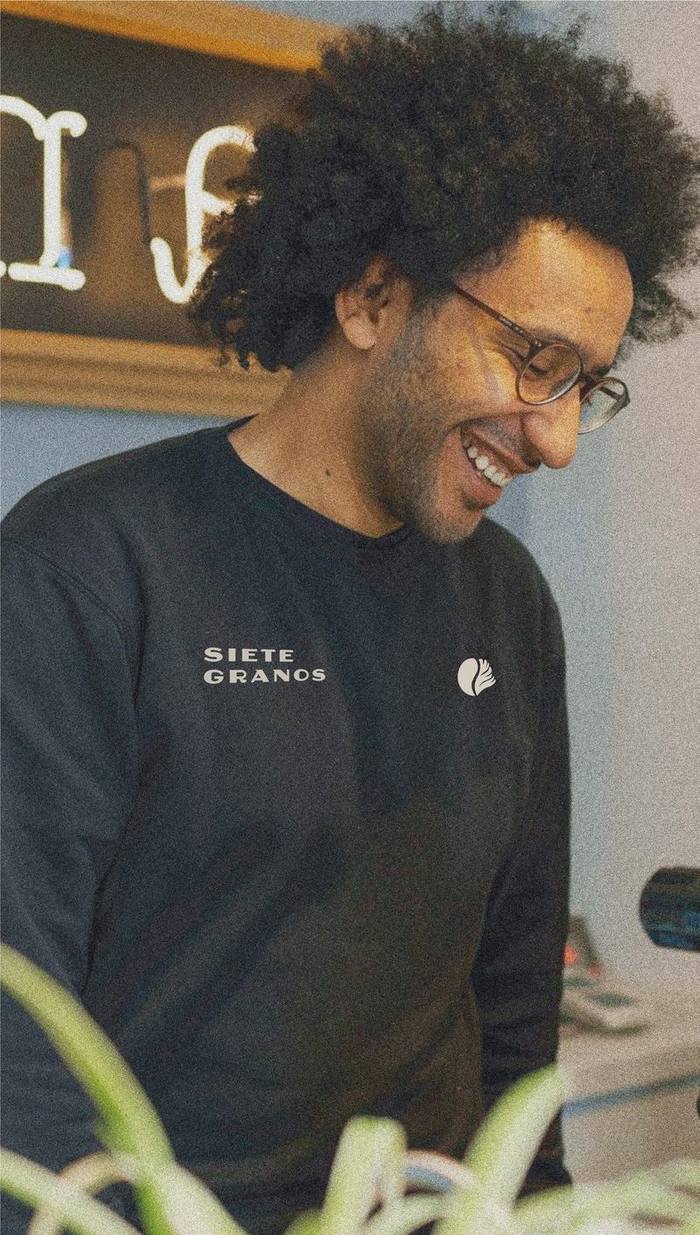 Barista sonriendo con sudadera Siete Granos